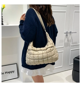 Detailed view of the large beige quilted puffer tote bag with wide shoulder strap design