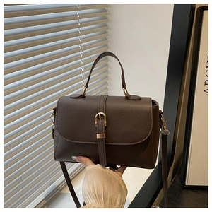 Close-up of dark brown lychee leather handbag featuring gold buckle and textured finish