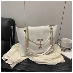 Detail of white tote bag featuring golden square lock, deer charm, and chain strap
