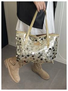 Detailed view of silver sequin tote bag with light beige handles and brand label