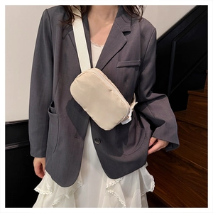 Close-up of cream nylon crossbody bag featuring adjustable fabric strap on model