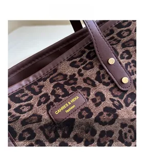 Close-up of leopard print tote bag featuring leather edge trim and embossed logo detail