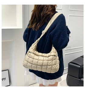 Detailed back view of a creamy quilted puffer tote bag worn by a model in a minimalist setting