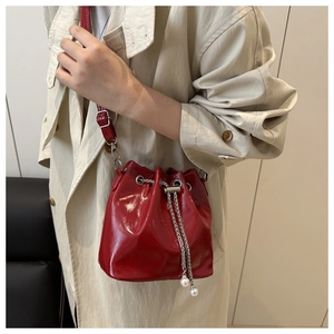 Detail of red patent leather bucket bag with silver chain drawstring and pearl charms