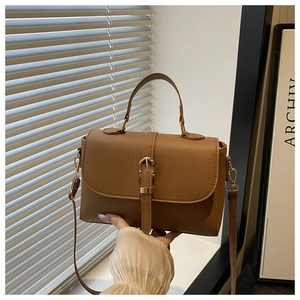 Detailed texture of brown litchi pattern leather bag with gold buckle and top handle