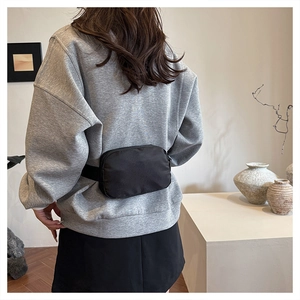 Minimalist black oxford crossbody bag worn by a model in a modern interior setting