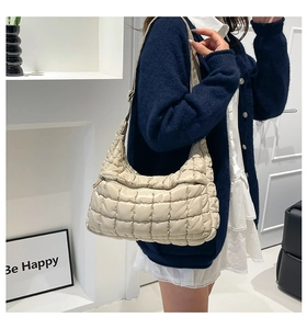 Detail of beige quilted puffer bag featuring soft cloud-like texture and wide strap