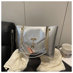 Detail of silver metallic tote bag with golden deer charm and chain shoulder strap