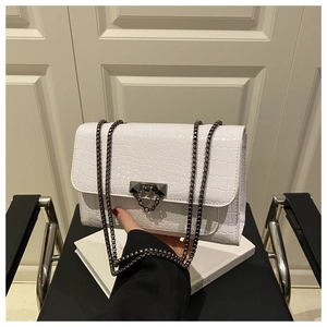 Detail of white crocodile pattern chain bag featuring a dark grey metal buckle and strap