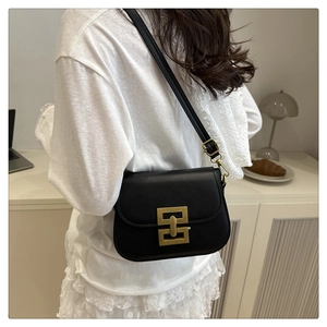 Detail of black leather saddle bag with gold geometric matte metal buckle on shoulder