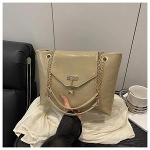 Detail of khaki tote bag featuring golden chain strap and iconic small deer pendant