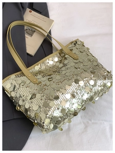 Detailed top view of large sequin tote bag with beige leather handles and fashion magazine