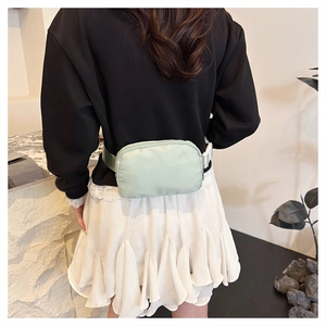 Detail view of mint green oxford crossbody bag with adjustable strap on a model