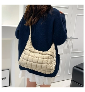 Detail of beige quilted puffer tote bag with square stitching on a fashion model