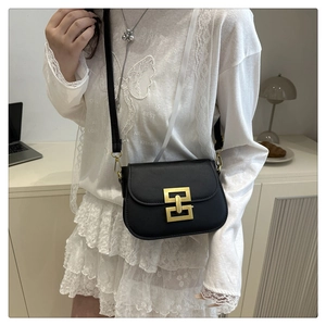 Classic black leather crossbody bag with a distinctive gold geometric buckle on a model