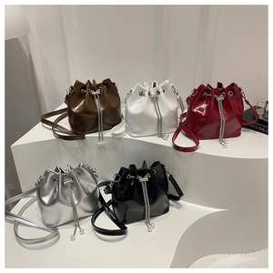 Detailed row of glossy drawstring bucket bags in five colors on geometric display