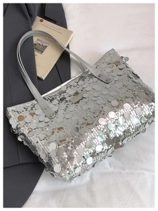 Detail of silver sequin tote bag showing metallic round sequins and thin leather handles