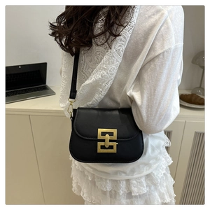 Detail of a vintage black leather crossbody bag with a distinctive golden metal buckle