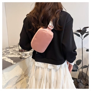 Back view of pink oxford fabric crossbody bag with adjustable strap on a female model