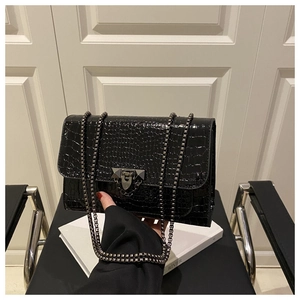 Close-up of black crocodile embossed leather handbag with gunmetal chain and buckle detail