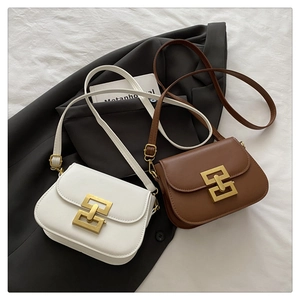 Close-up of elegant ivory and brown crossbody bags with golden metal clasps