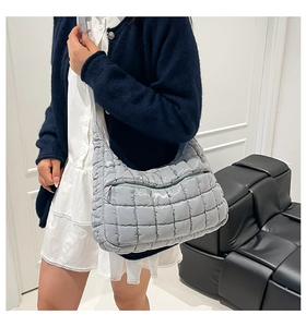 Detail of light grey quilted tote bag featuring glossy fabric and square stitching