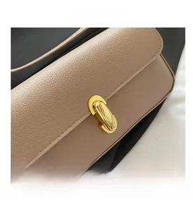 Dettaglio di una borsa sottospalla beige con chiusura girevole in metallo dorato di lusso