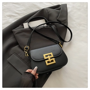 Detail of elegant gold double interlocking buckle on a black leather square handbag