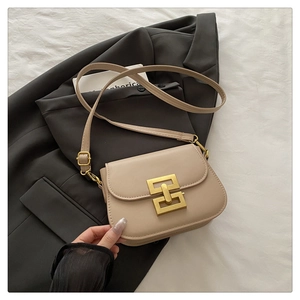 Close-up of beige crossbody bag with gold geometric lock on grey professional suit
