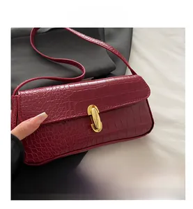 Detail of red crocodile texture leather bag with a gold metal clasp and fine stitching