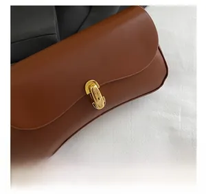 Détail du sac baguette marron vintage avec une boucle métallique élégante dorée en forme de U
