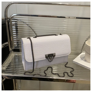 Close-up of white crocodile pattern flap bag with dark grey metal chain and lock detail