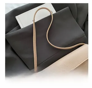 Dettaglio della borsa beige in pelle martellata con chiusura a scatto ovale in oro