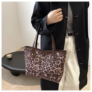 Detailed view of leopard print tote bag with brown leather trim and gold rivet accents