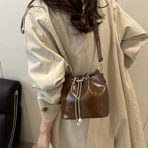 Deep brown glossy bucket bag with pearl chain drawstring and leather shoulder strap