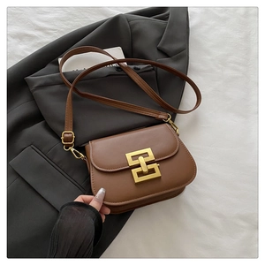 Detail of vintage brown leather handbag with gold geometric buckle on grey suit