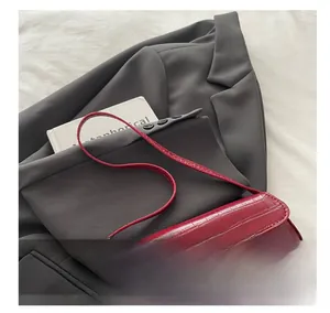 Detail of red crocodile texture baguette bag with gold metal buckle on a grey suit jacket