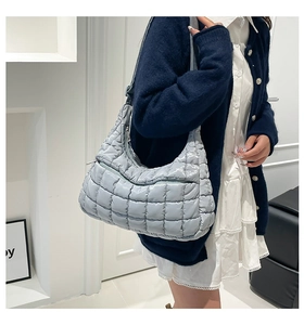 Detail of light blue-grey quilted puffer tote bag on a model wearing a cardigan