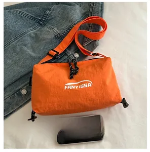 Close-up of orange waterproof nylon crossbody bag with logo on denim background