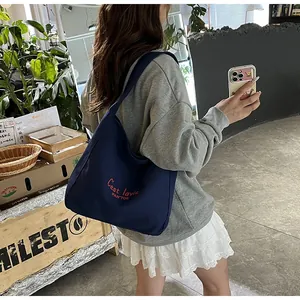 Détail d'un sac cabas en toile bleu marine avec broderie rouge pour un style décontracté