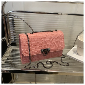 Close-up of pink faux-crocodile leather texture and gunmetal chain buckle detail