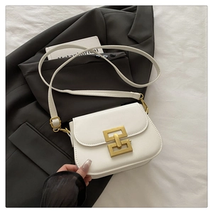 Detail of white leather crossbody bag featuring a golden geometric clasp and soft texture