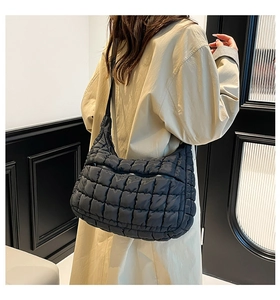 Detail view of black quilted tote bag with adjustable shoulder strap on female model