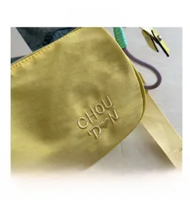 Vue détaillée du sac polochon en nylon jaune avec broderie et bandoulière tressée
