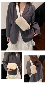 Detail of adjustable strap and buckle on cream nylon crossbody bag worn by model