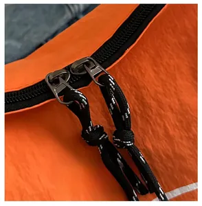 Close-up of orange waterproof nylon bag with black dual zippers and cord pulls