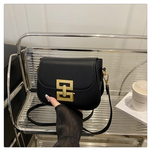 Detailed view of black faux leather crossbody bag with elegant gold rectangular clasp buckle