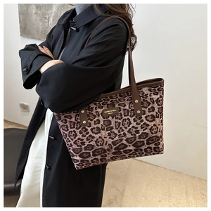 Detail of leopard print tote bag with brown PU straps and metallic rivet accents