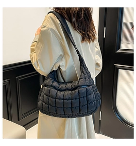 Quilted black puffer hobo bag shown on a model wearing a classic beige trench coat