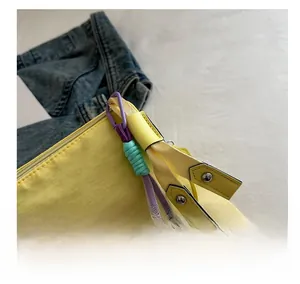 Détail du sac bandoulière jaune avec pendentif en corde tressée et lettres gaufrées